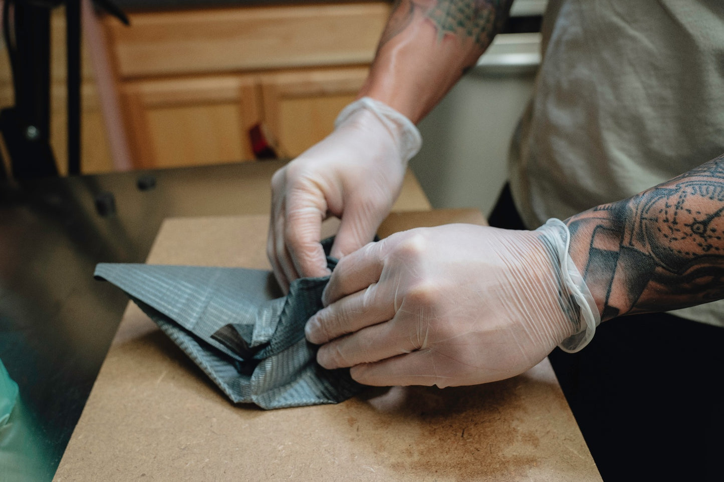 Vinyl Disposable Gloves showcased on a tattoo artist's hands setting up his station