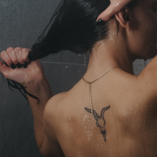 Person in the shower with water flowing over a back tattoo.