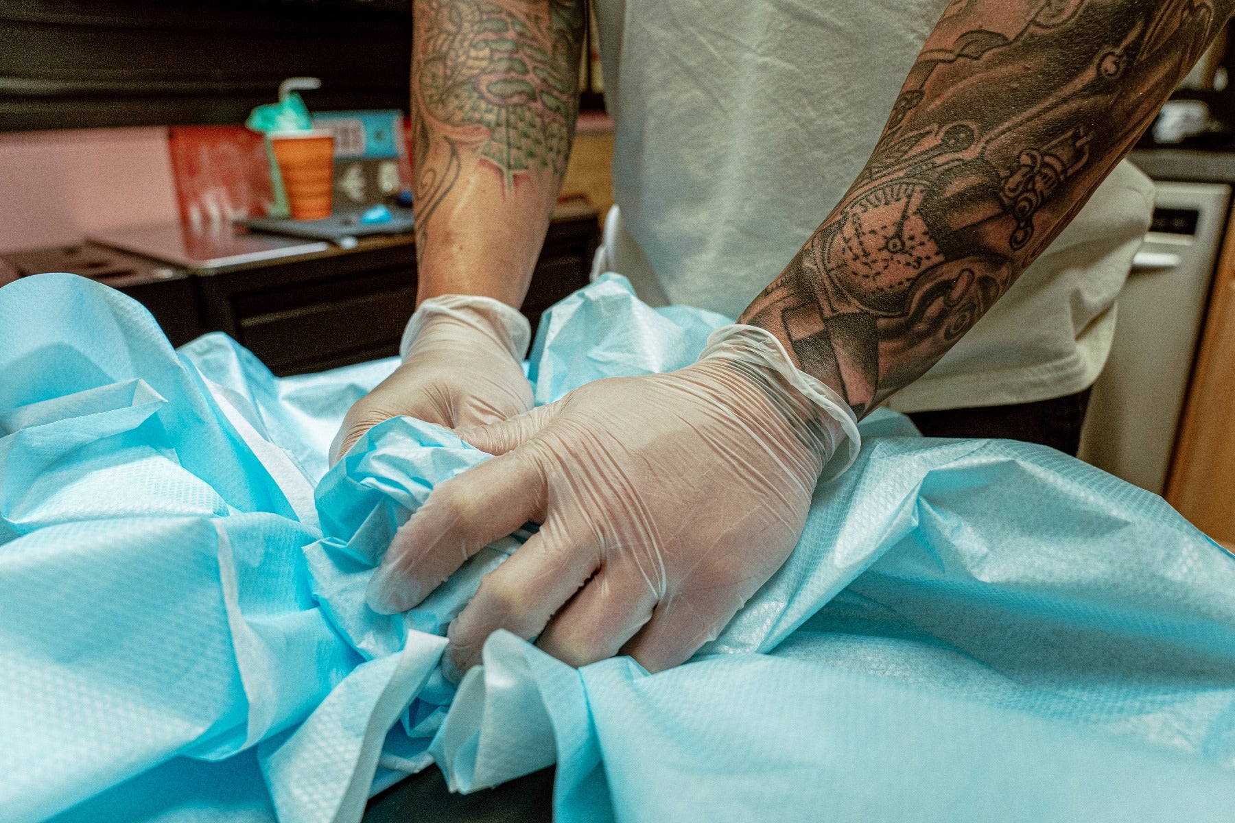 Vinyl Disposable Gloves showcased on a tattoo artist's hands setting up his station
